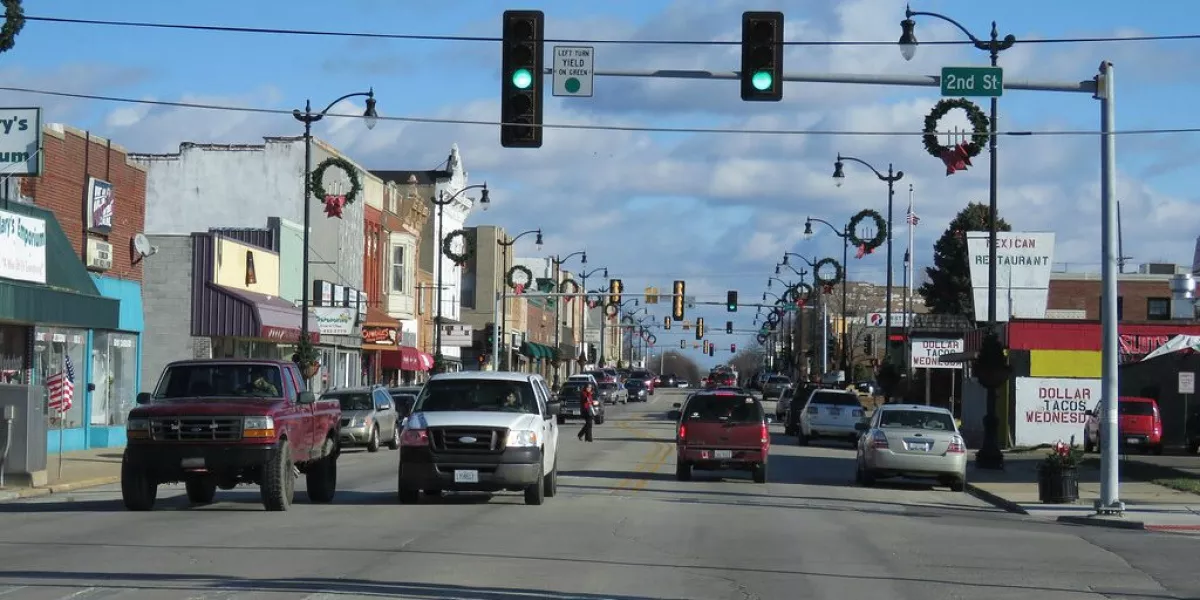 cars at a traffic light with wreaths on poles